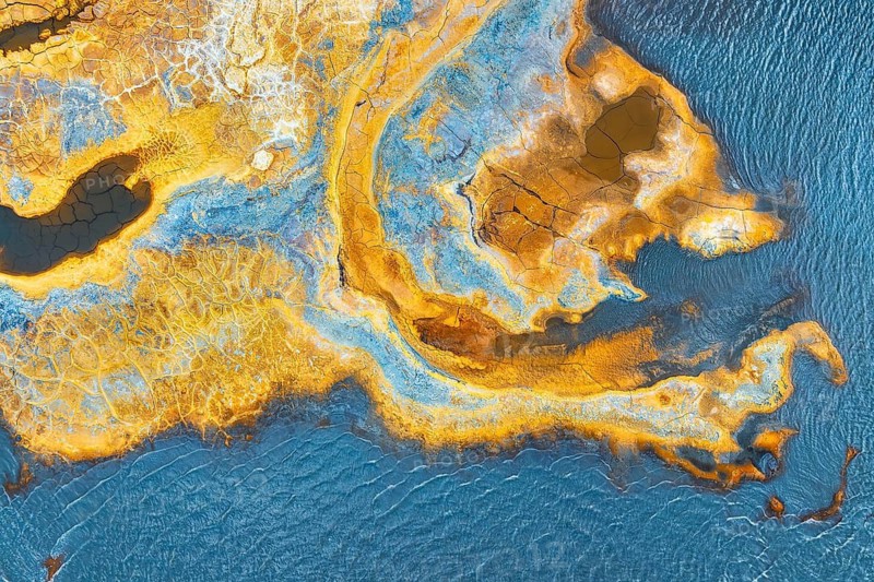 A vivid aerial snapshot featuring a multicolored, abstract landscape with intricate patterns and textures resembling an artistic painting
