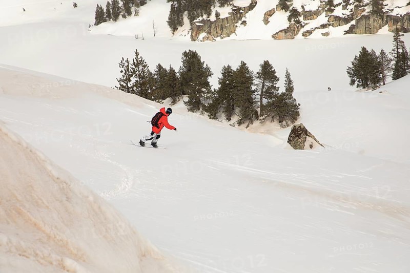 A snowboarder in a vivid red jacket glides effortlessly through untouched mountain powder, showcasing the thrill and beauty of backcountry snowboarding adventure