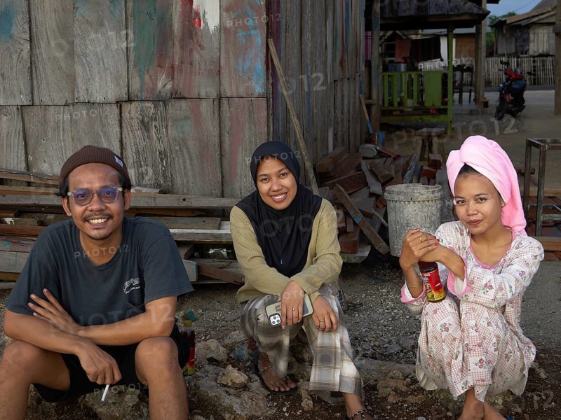 Muslim woman and man in village sitting in front of hut, Tana Beru, Sulawesi, Indonesia
