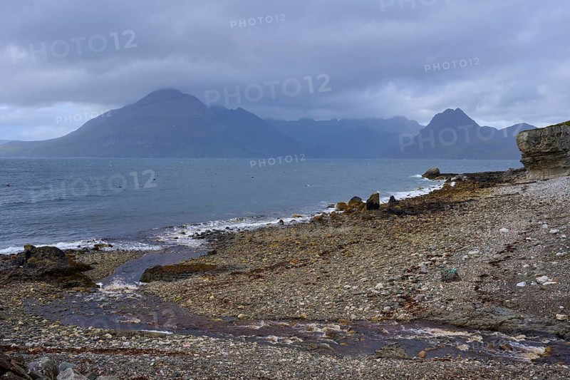 View of a cloud-covered coastal landscape with mountains and pebble beach by the sea, Elgol Beach, Elgol, Isle of Skye, Scotland, United Kingdom, Great Britain