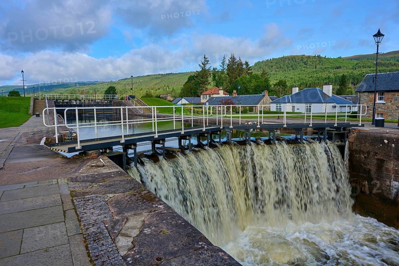 A waterfall in a lock surrounded by buildings and vegetation, Caledonian Canal, Fort Augustus, Loch Ness, Scotland, United Kingdom, Great Britain