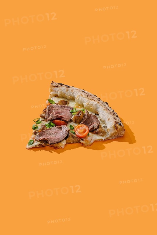 Delicious pizza slice, tastefully topped with roast beef, truffle sauce, mozzarella, porcini mushrooms, and fresh cherry tomatoes. Generously garnished with green onions on a vivid orange background