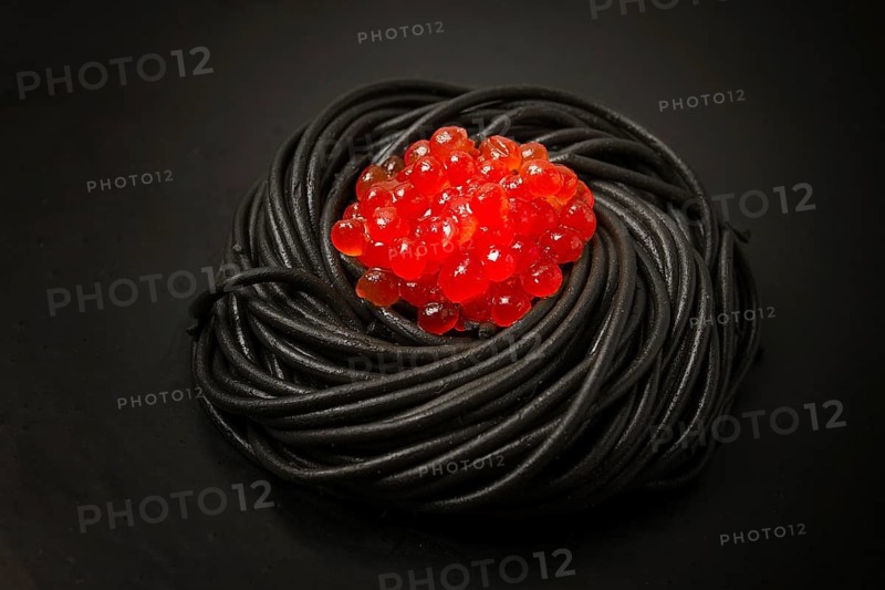 Black spaghetti with red caviar, pasta, on a black background, top view, no people