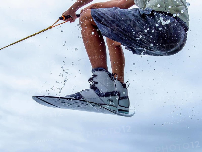 Young man jumping with wakeboard, water sports, water skiing in wakepark