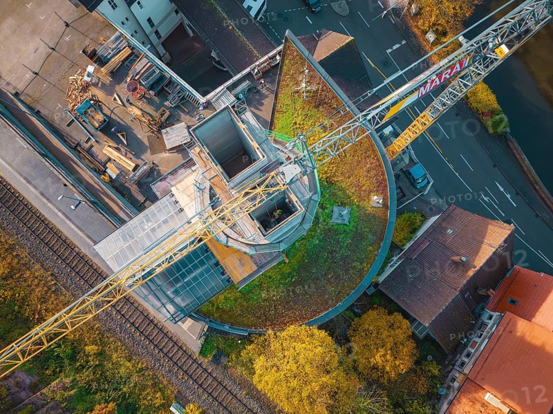 Drone shot of a construction site with crane in an urban environment near a railway line, ZOB Calw reconstruction for Hermann Hessebahn, Calw, Black Forest, Germany