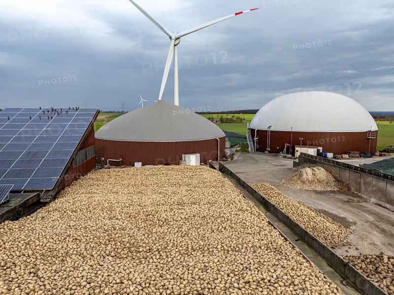 Biogas plant produces gas from various biomass, here the sugar beet store, the electricity is produced in combined heat and power plants with the biogas produced and sold to companies in the neighbouring industrial estate, the heat generated is fed into a local heating network, gas storage technical building with solar roofs and wind power plant, Ense, North Rhine-Westphalia, Germany
