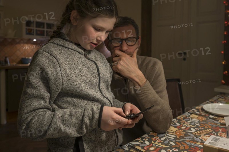 Father and daughter looking for something with their mobile phone, Mecklenburg-Vorpommern, Germany