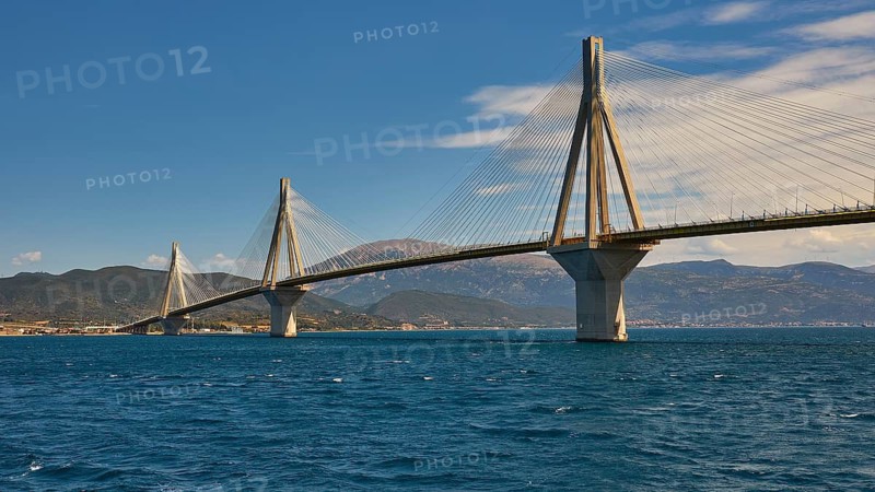 Cable bridge stretches across wide sea with slightly cloudy sky, Rio-Antirrio cable bridge, Patras, Peloponnese, Greece