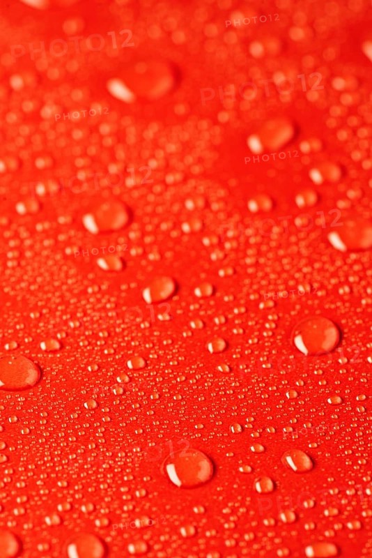 Close up of water droplets scattered on a vibrant red textured surface, creating a fresh and dynamic visual effect. The image captures the essence of moisture and color contrast