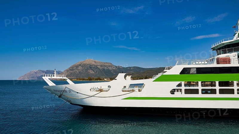 Large ferry with green accents, calm blue sea and mountain scenery in the background, Rio-Antirrio ferry, cable car bridge, Gulf of Corinth, Patras, Peloponnese, Greece