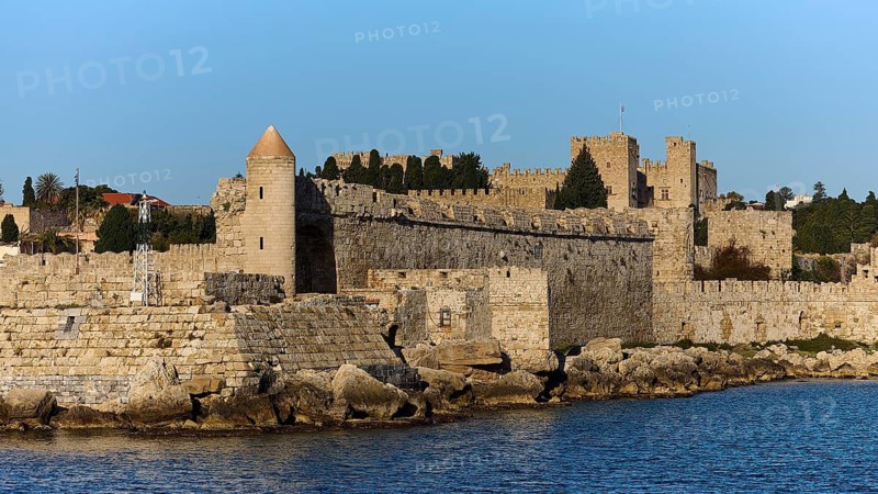 Massive fortress wall with battlements rises near the water, Rhodes Old Town, Rhodes, Dodecanese, Greek Islands, Greece