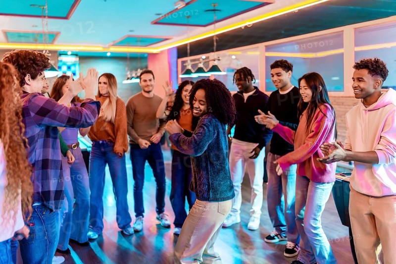 Multiethnic friends dancing and having fun together in a vibrant bowling alley, enjoying the music and nightlife atmosphere