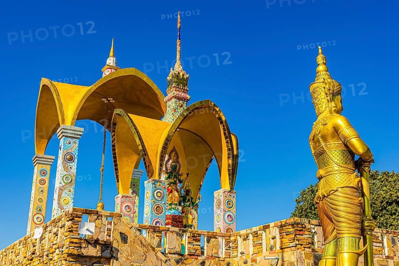 Round arch pavilions decorated with colorful mosaics and glass works of art, in front of a gilded temple guard, Buddhist temple complex Wat Phra That Sorn Kaew, Phetchabun province, Thailand