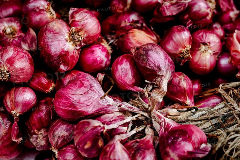 A vibrant pile of fresh red onions, vivid in color, neatly tied in bunches, displayed in a bustling Hong Kong market