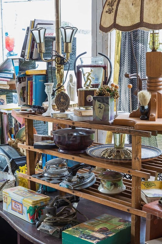 Various objects for sale on wooden shelves inside second hand goods and chattels store, Quebec, Canada