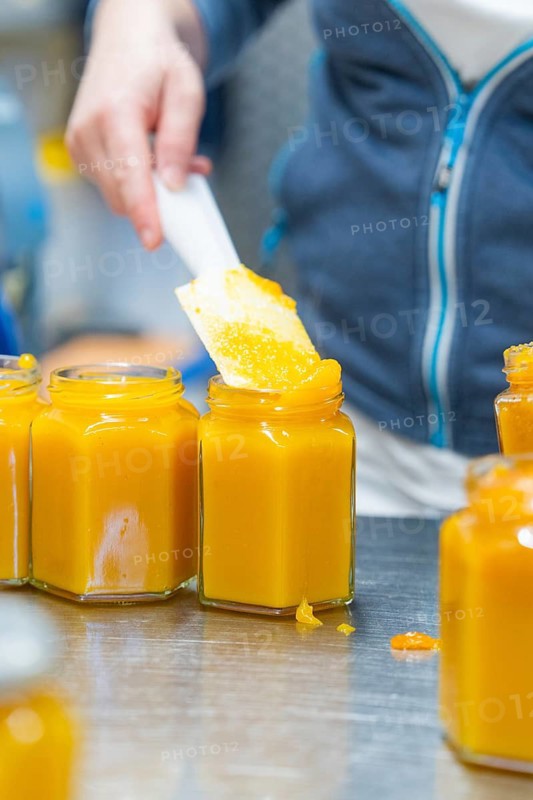 Person filling yellowish jam with a spatula into a hexagonal jar, jam production, Haselstaller Hof, Wildberg Gültlingen, district of Calw, Black Forest, Germany