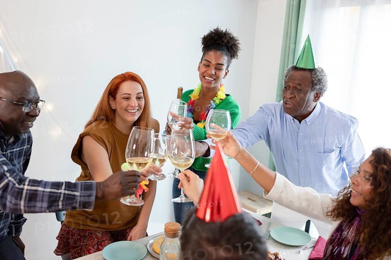 A joyful group of friends raising glasses for a birthday toast. The room is adorned with festive decorations, party hats, and a lively atmosphere, capturing a moment of celebration