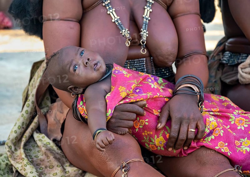 Baby in the arms of a Himba woman, traditional Himba village, Kaokoveld, Kunene, Namibia