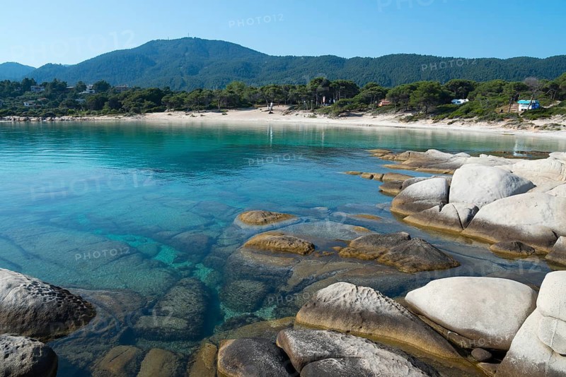 Crystal clear water and rocks in front of wooded mountains, Karidi beach, Karydi, Vourvourou, Sithonia, Chalkidiki, Central Macedonia, Greece