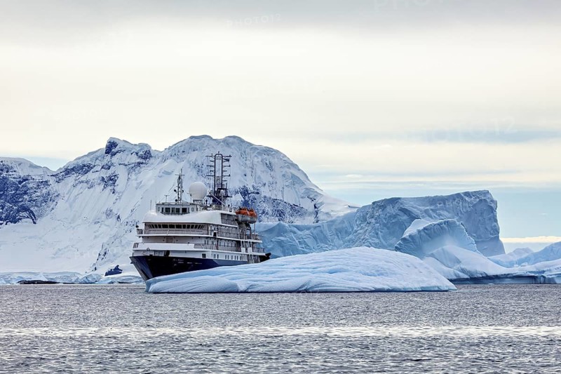 A large ship navigates through icy waters, surrounded by impressive glaciers, cruise ship underway in the Southern Ocean in Antarctica