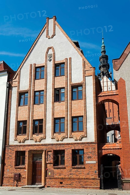 An imposing historic building with vertical structures, decorated with brick elements, against a blue sky, St. Nicholas Church, in front of it a 13th century church path, Elblag, Elblag, Warminsko-Mazurskie, Warminsko-Mazurskie Voivodeship, Poland