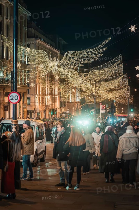 Angel decoration and lights accompany people on busy street, New Year's Eve London, Great Britain