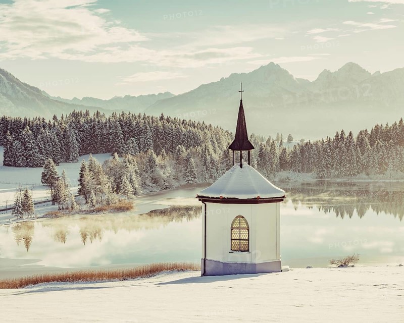 Chapel by the lake in the wintry snow-covered Allgäu near Halblech in front of an impressive mountain landscape, Bavaria, Germany