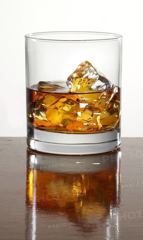 Whisky neat on ice cube cubes in a tumbler on a bar counter, studio shot