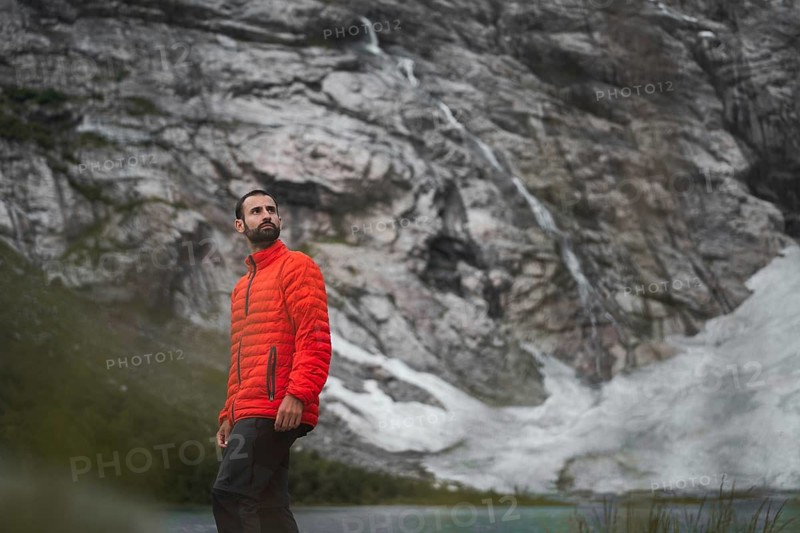 A man in a red jacket explores the stunning mountainous landscapes of Norway Perfect moment captured in trekking and camping adventure Serene, adventurous, and inspiring