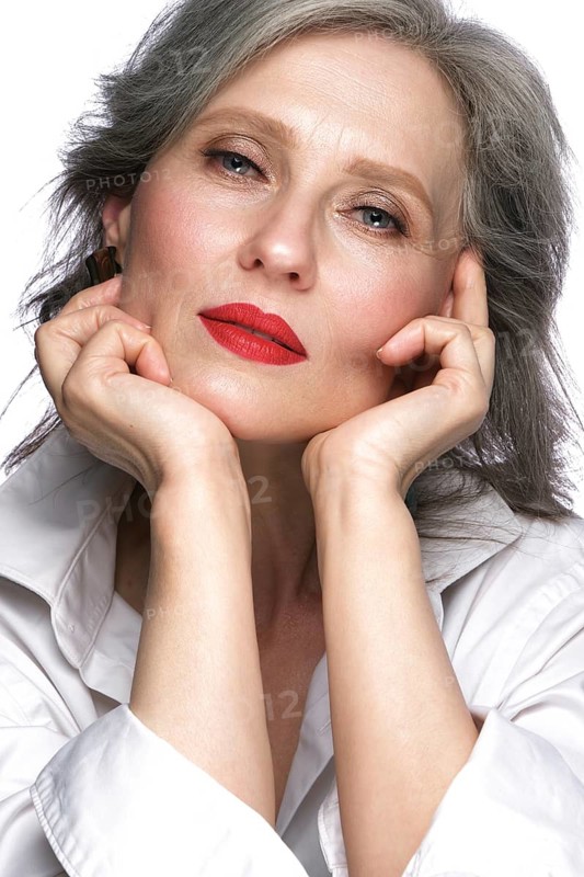 Portrait of a beautiful elderly woman in a white shirt with classic makeup and gray hair