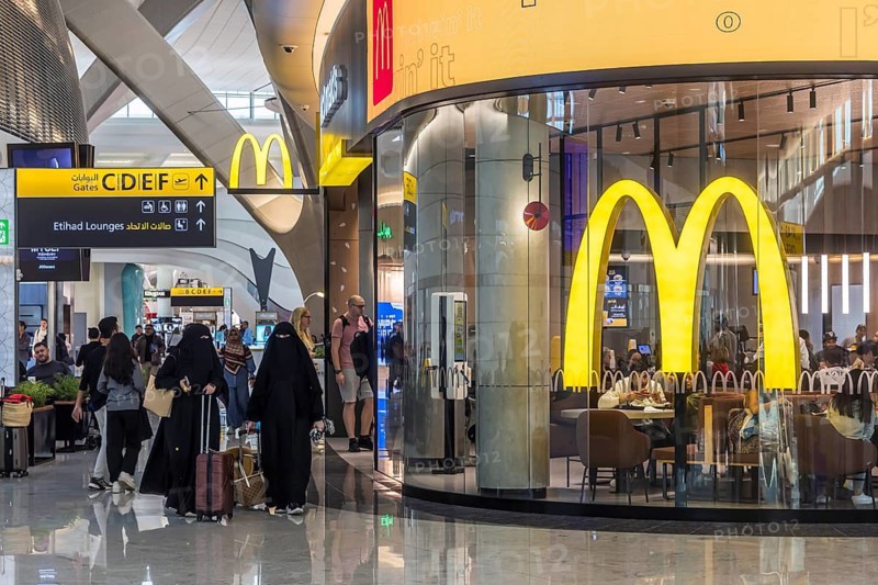 Abu Dhabi Airport, Zayed International Airport with passengers. McDonalds restaurant. The new Terminal A has a capacity of 45 million passengers per year. Modern architecture. Abu Dhabi, United Arab Emirates, UAE