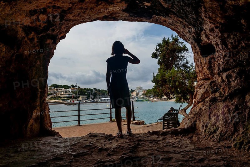 Tourist shielding her eyes from the sun while enjoying the view of the port of puerto cristo, mallorca