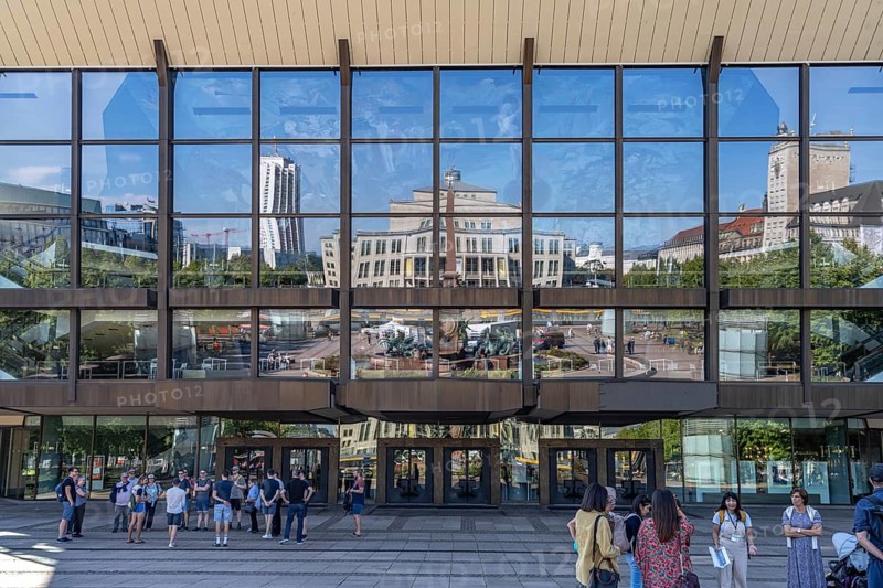 Mendebrunnen and Leipzig Opera are reflected in the façade of the Gewandhaus on Augustusplatz, Leipzig, Saxony, Germany