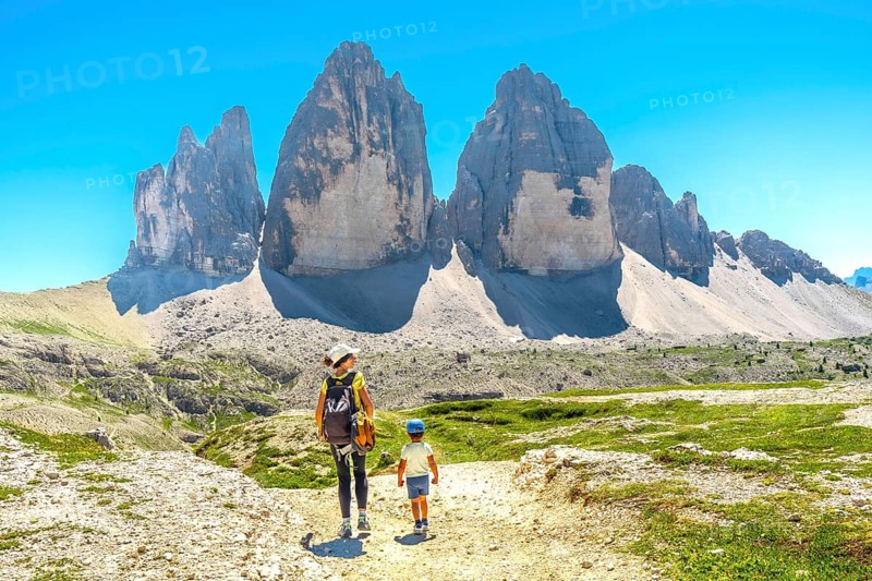 Tourists hiking on a trail with the tre cime di lavaredo in the background, dolomites, italy