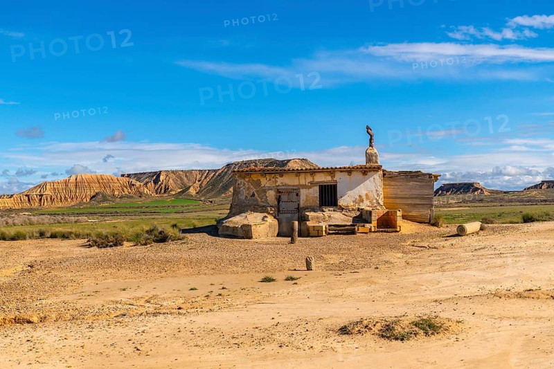 Old abandoned building standing in the arid landscape of the bardenas reales desert in navarre, spain, under a vibrant blue sky