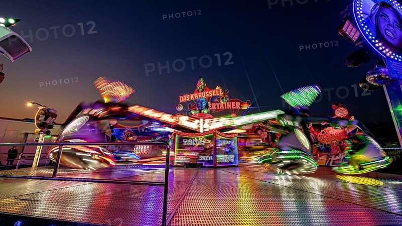 Blurred carousel in lively motion at a fair at night, carousel and hustle and bustle of summer profit in Eisenach