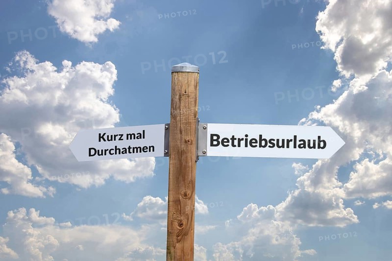 (Photo montage) Freestanding signpost against a blue sky points in various directions COMPANY VACATION and TAKE A QUICK BREATH
