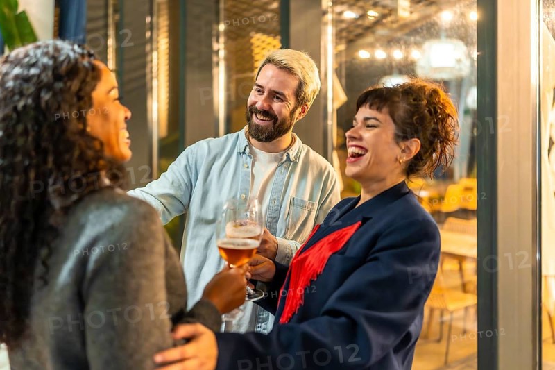 Multi-ethnic happy modern friends congratulating a woman during night party on bar terrace
