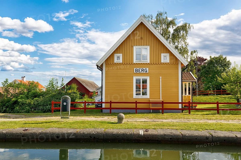 Charming yellow wooden house, lock keeper's house, sign with inscription, lock stairs near mountain, Göta Canal, Östergötland, Sweden