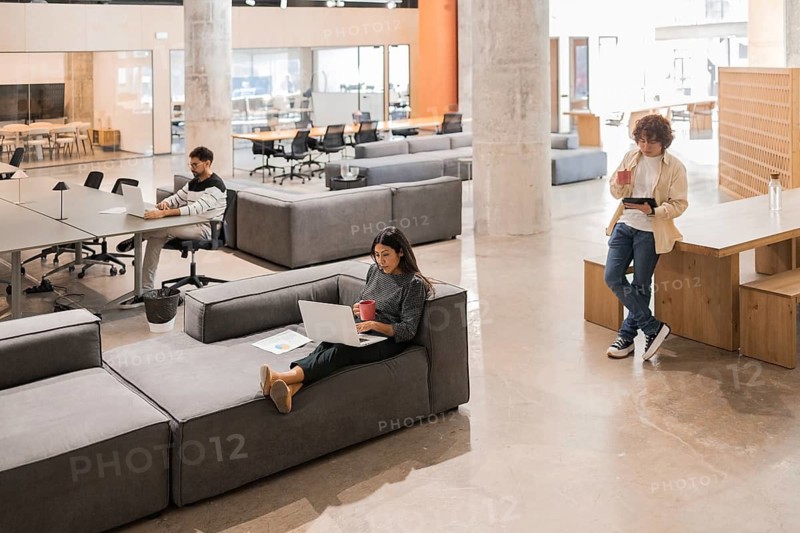 A contemporary open office space with professionals engaged in various tasks The environment fosters collaboration and creativity with relaxed seating and shared tables