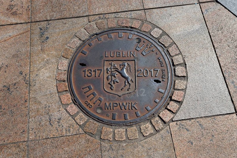 Bronze manhole cover with the coat of arms of Lublin and dates on paving stones, manhole cover, manhole cover, Lublin, Poland