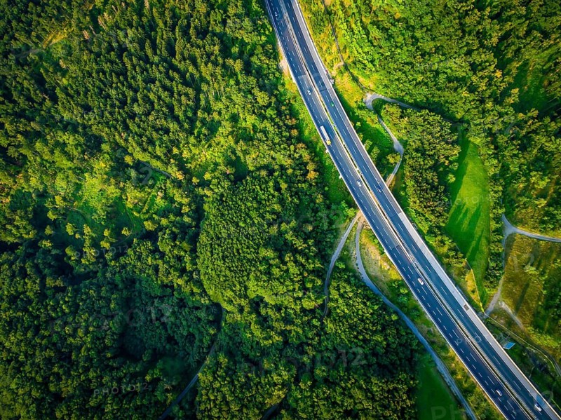 Aerial dramatc view to the road with lorry and many cars and green forest around in the summer.Alps.Slovenia