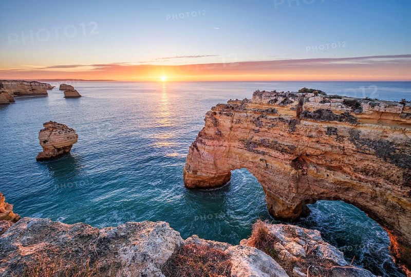 Sunrise at Praia da Marinha beach in Algarve, Portugal, with ocean cliffs, sea stacks and quiet morning shoreline