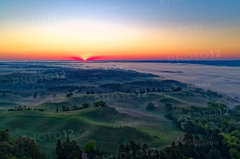 Sunrise over the hilly landscape of the Uckermark on the edge of the Oder Valley and morning fog over the Lower Oder Valley National Park. aerial view. Stützkow, Schwedt, Brandenburg, Germany