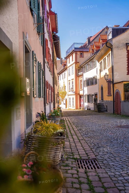 Idyllic old town alleyway with cobblestones and colorful houses in sunlight, Bregenz, Austria