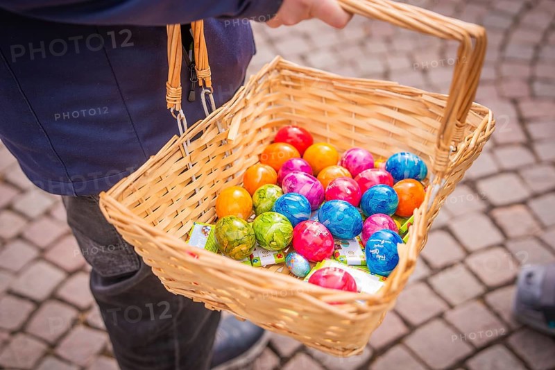 Woven basket with colorful Easter eggs is being held on a paved road, Easter campaign, Sindelfingen, Böblingen district, Germany