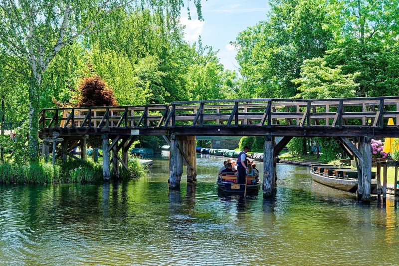 A boat with tourists sails under a jetty on one of the branches of the Spree in the Spreewald, UNESCO Spreewald Biosphere Reserve. Lübbenau, Oberspreewald-Lausitz, Brandenburg, Germany