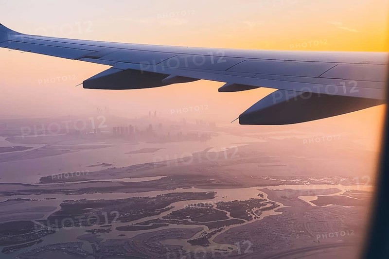 Passengers point of view window panorama of Abu Dhabi skyline and city with rivers and deserted landscape on sunset. Fly with low budget airlines holidays in UAE concept