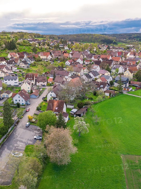 Aerial view of a small village with densely packed houses and surrounding green fields, Ostelsheim, district of Calw, Germany