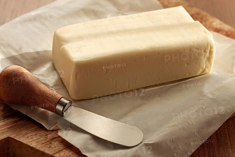 Butter briquette, on wrapping paper, wooden chopping board and butter knife, breakfast, rustic style, no people